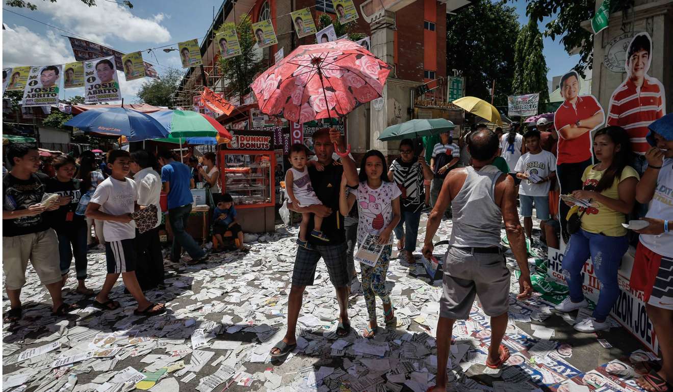 Filipinos walk along trash surrounding a public school turned into a polling precinct in Manila, Philippines. Photo: EPA