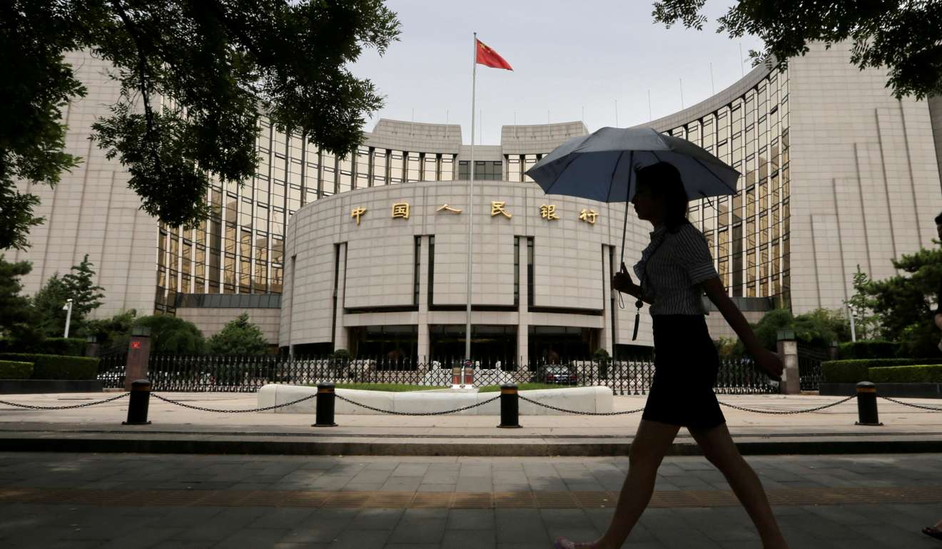 A woman walks past the headquarters of the People's Bank of China in Beijing. Photo: Reuters