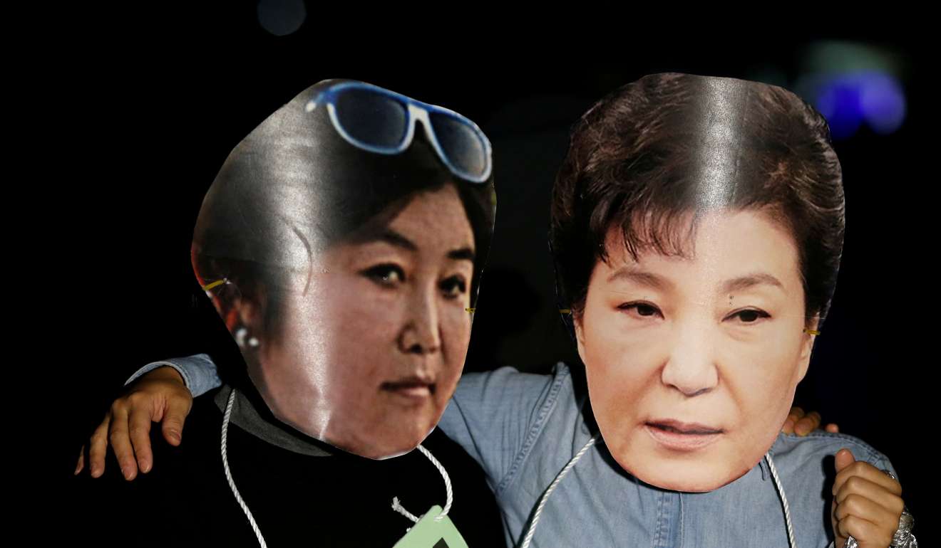 Protesters wearing cut-out masks depicting Park Geun-hye and Choi Soon-sil. Photo: Reuters