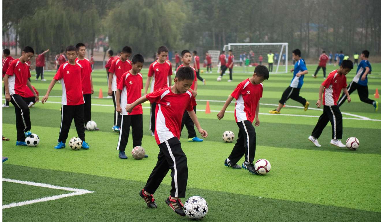 This picture taken on October 20, 2016 shows students taking part in football practice at the Tagou martial arts school in Dengfeng. Some 1,500 students from the vast Tagou martial arts school, a few miles from the cradle of Chinese kungfu, the Shaolin Temple in Henan province, have signed up for its new soccer programme, centred on a pristine green Astroturf football pitch where dozens of children play simultaneous five-a-side-games. / AFP PHOTO