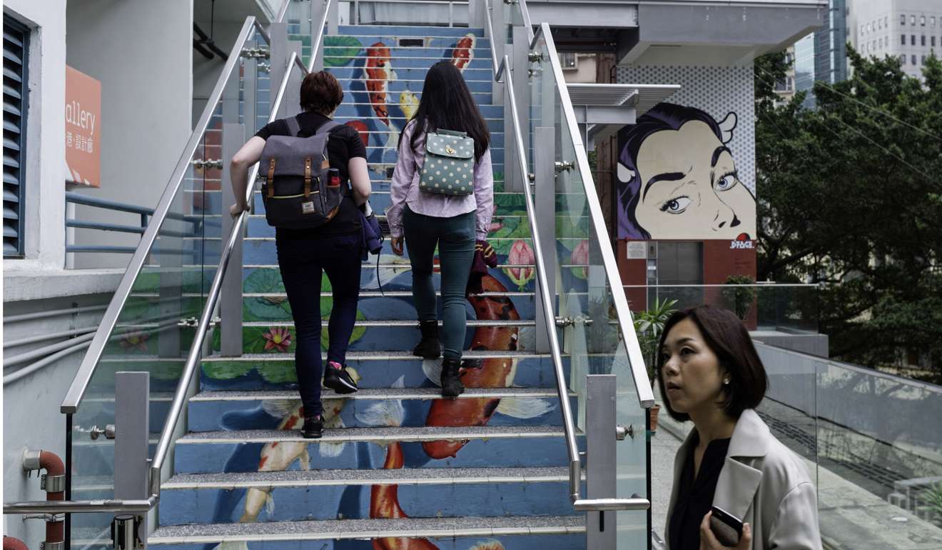 Visitors walk up stairs adorned with artwork at the former Police Married Quarters (PMQ) building, which now houses design studios and creative enterprises, in Hong Kong's SoHo district. Photo: AFP