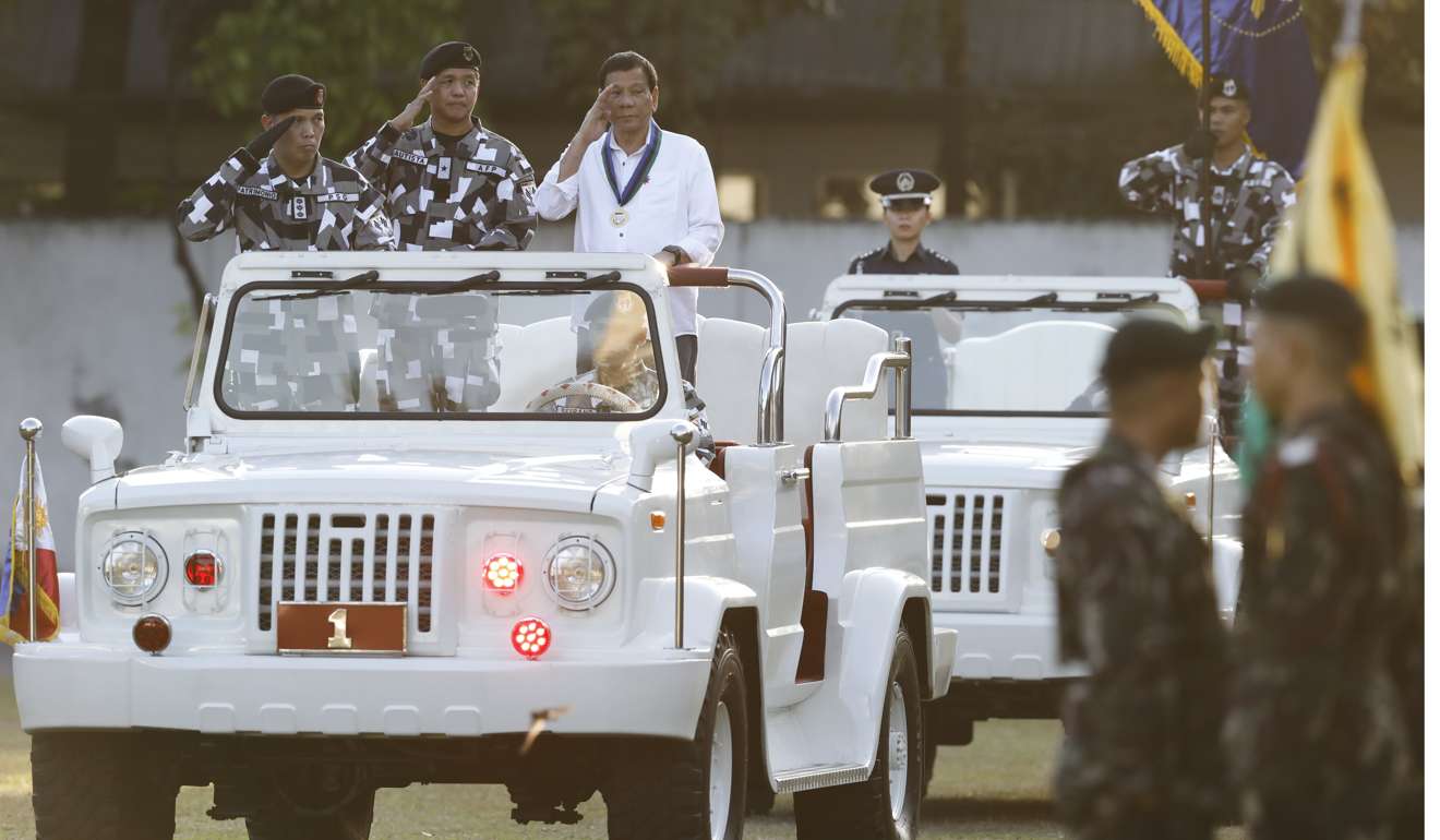 Philippine President Rodrigo Duterte salutes from a vehicle during a military ceremony. Photo: EPA