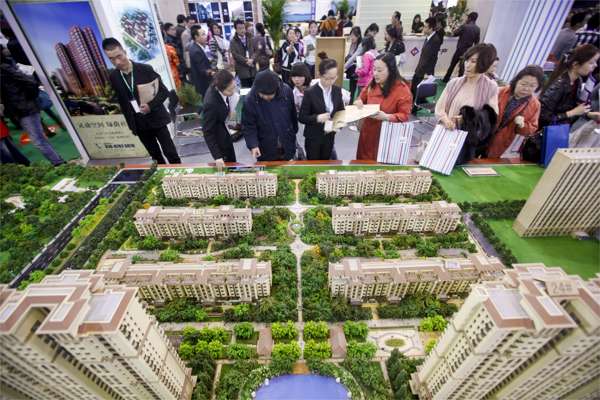 People look at models of new residential developments for sale at a real estate fair in Beijing. Local authorities in the Chinese capital announced nine restrictive measures in 10 days. Photo: EPA