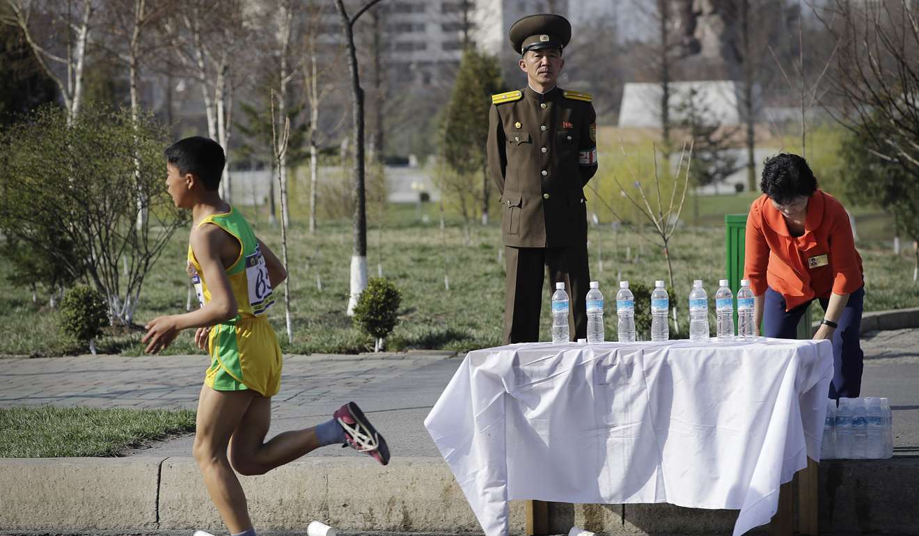 A North Korean military soldier stands on duty while a participant of the Pyongyang marathon runs past a water station. Photo: AP