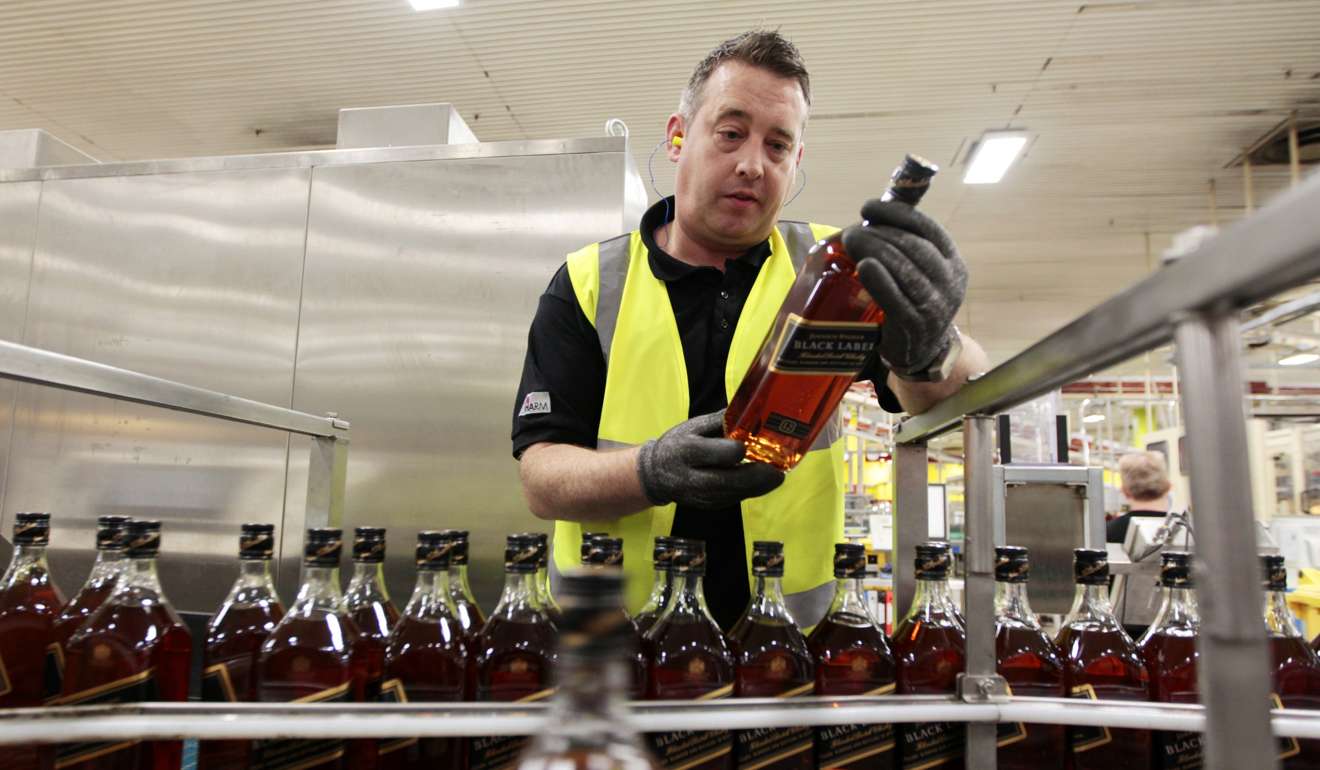A worker looks at bottles of Johnnie Walker whisky on a Diageo production line in Glasgow, Scotland. Photo: Reuters