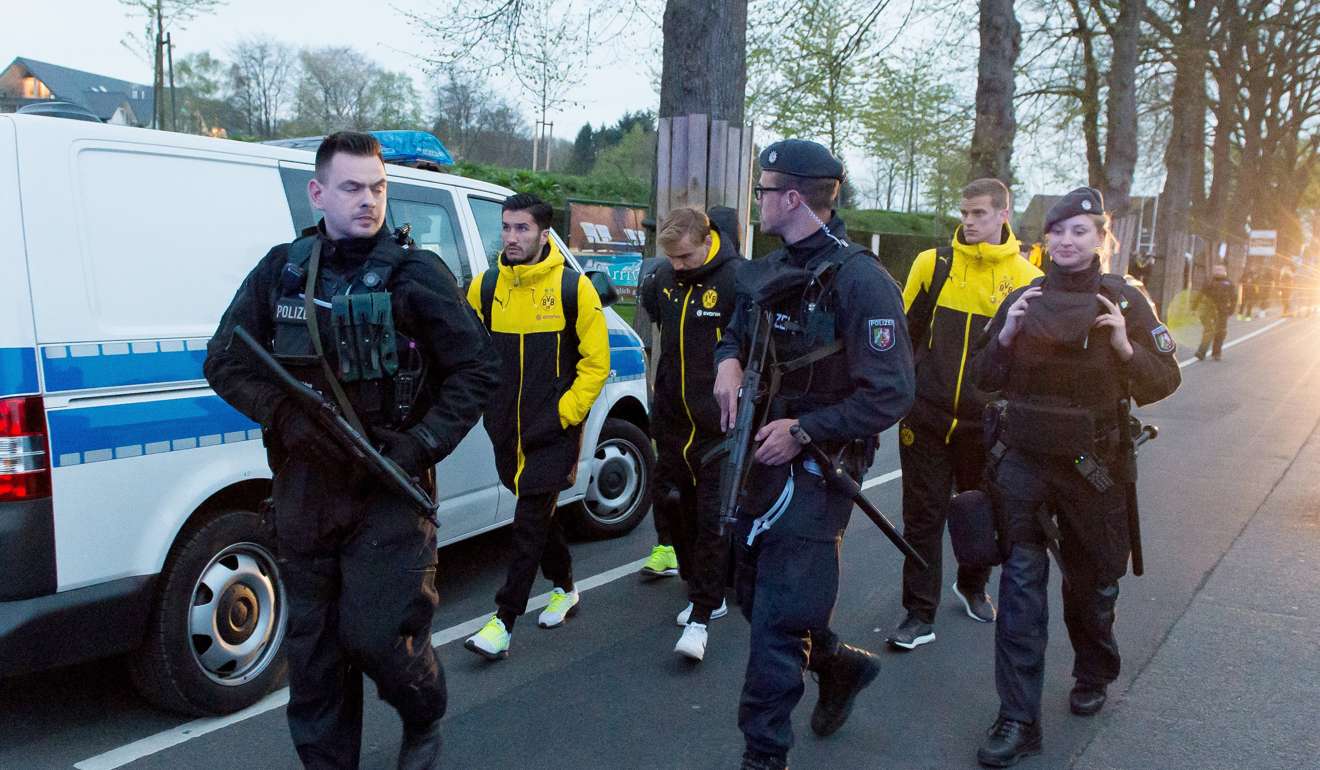 Borussia Dortmund players (L-R) Nuri Sahin, Marcel Schmelzer and Sven Bender are escorted by police after their team bus was hit by three explosions. Photo: EPA