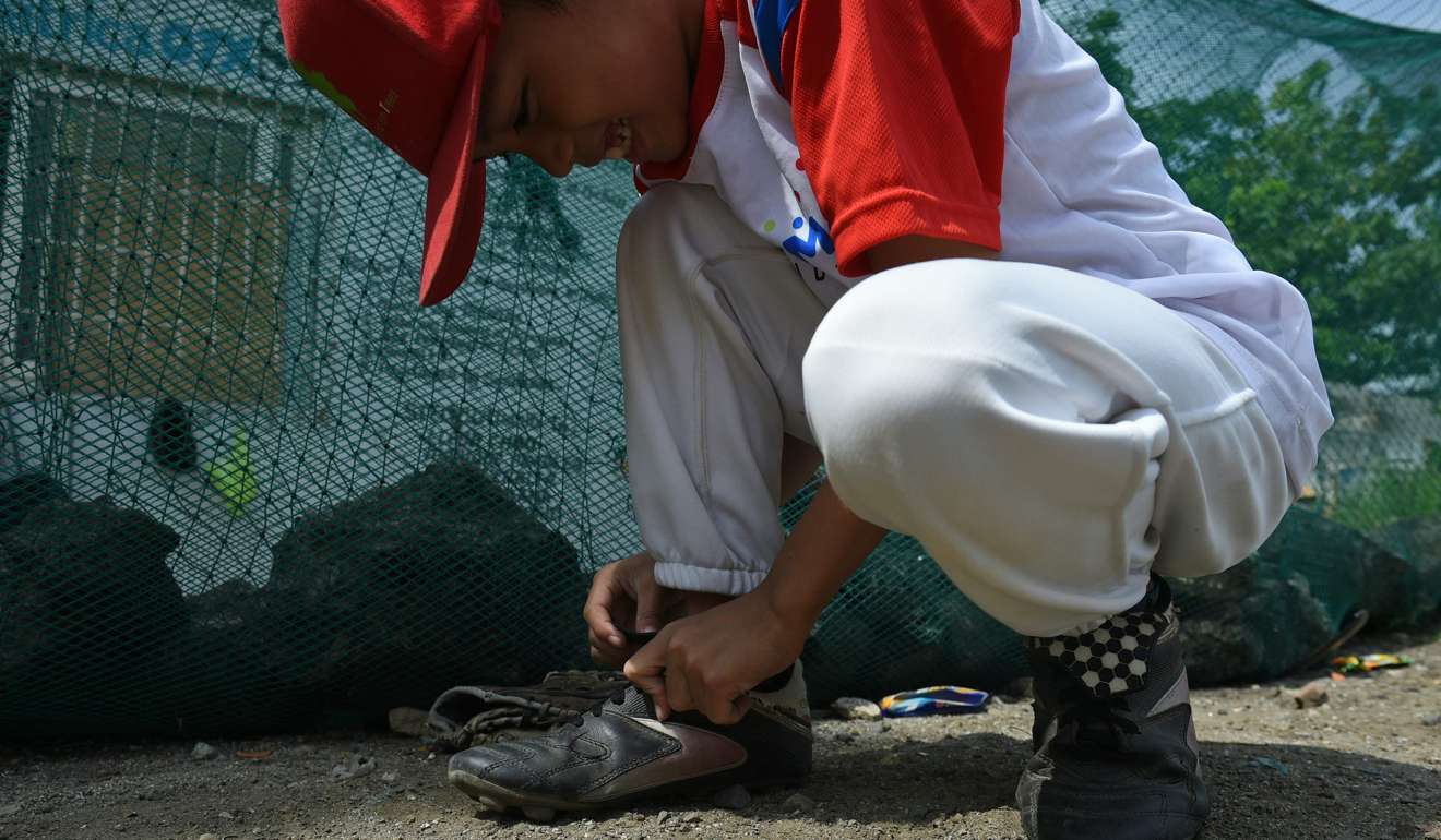 A member of the Smokey Mountain baseball team, who plays at a former dumpsite in Manila, ties his laces before practice. Photo: AFP