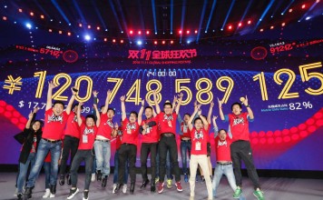 Staff members celebrate in front of a giant screen displaying total gross merchandise volume (GMV) of Alibaba's online marketplace Tmall for the Singles' Day shopping spree in Shenzhen. Photo: Xinhua