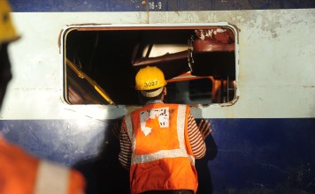 A rescue worker searches for survivors in the wreckage of a derailed train near Pukhrayan in Kanpur district. Photo: AFP