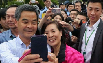 A visitor poses with Chief Executive Leung Chun-ying for a picture during the Government House annual open day in Central. Photo: Felix Wong