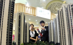 A sales assistant speaks to a customer in front of a model of a residential complex, at a real estate exhibition in Shanghai. Recent property cooling measures have dented demand for residential mortgages. Photo: Reuters