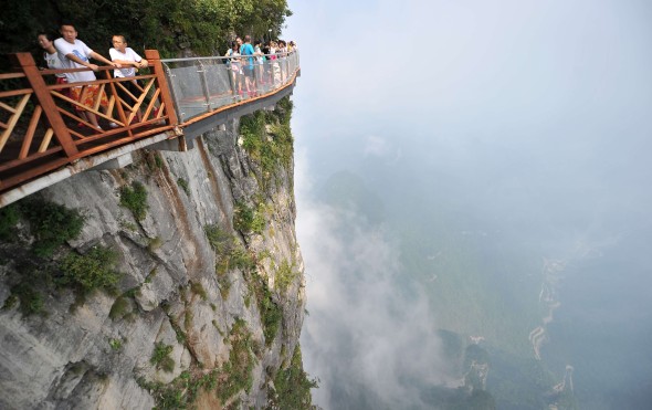 Tourists walk on the 100-meter-long and 1.6-meter-wide glass skywalk overlooking the "Tianmen Tongtian Avenue" on the cliff of Tianmen Mountain (or Tianmenshan Mountain) in Zhangjiajie National Forest Park in Zhangjiajie city, central China's Hunan province. Photo: Imaginechina