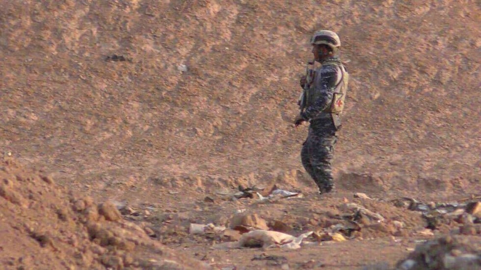 An Iraqi soldier stands guard at a mass grave containing 100 beheaded bodies in the village of Hamam al-Alil, south of Mosul on Monday. Photo: Washington Post / Iraqi Federal Police.