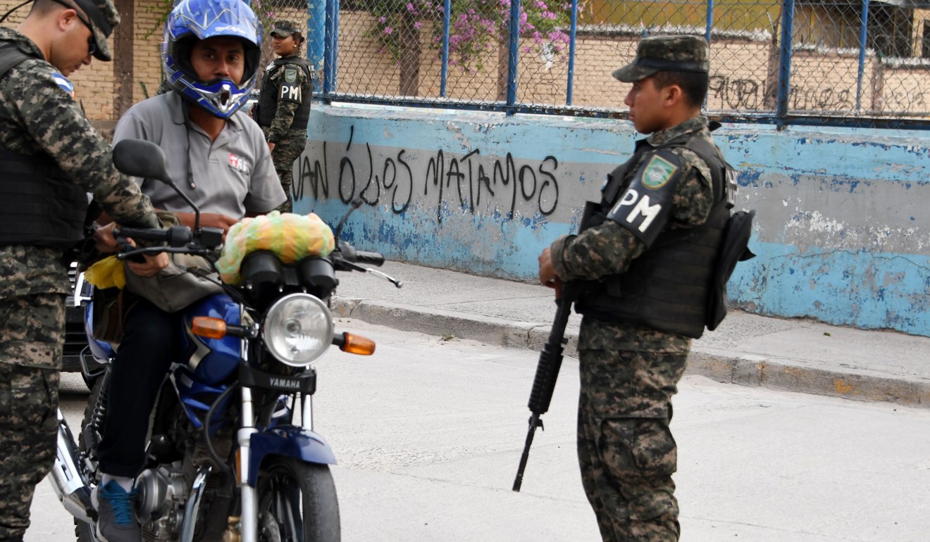 Soldiers check a motorcyclist's papers in an MS-13-controlled area of Honduras. Photo: AFP