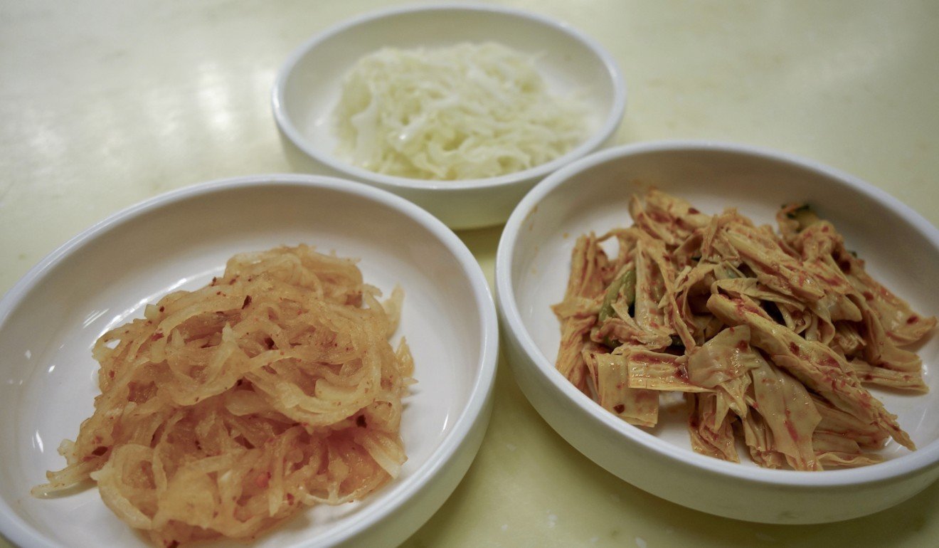 Banchan – small side dishes – of chilled spiced radish, cabbage, and dried tofu skins with pickles.