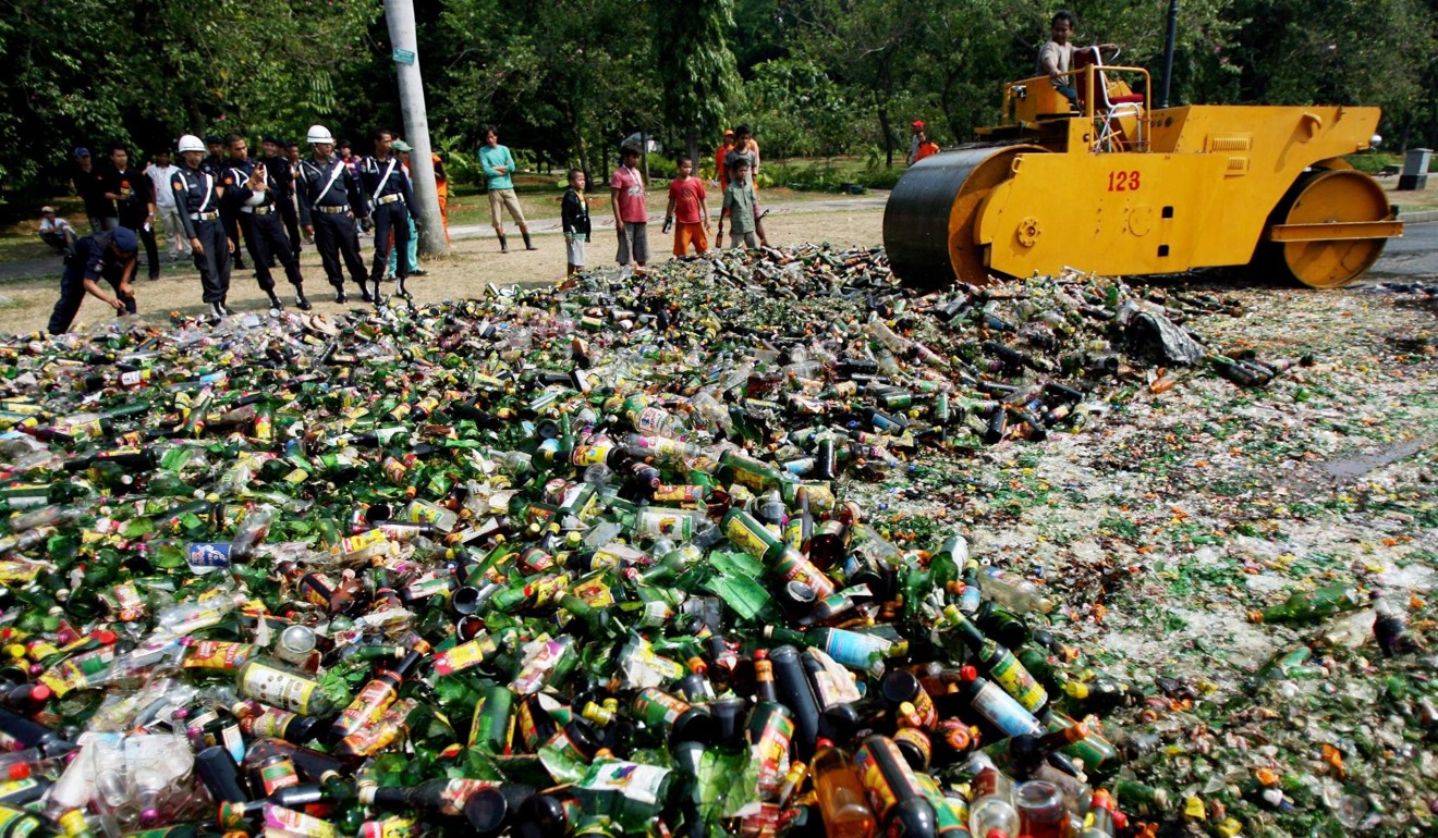Indonesian officers destroy alcohol drinks seized during the holy month of Ramadan. Photo: EPA