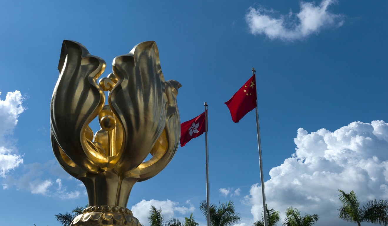 The flags of Hong Kong and the People's Republic of China fly next to the Golden Bauhinia statue in Hong Kong. The statue is located next to the Convention Centre where the ceremonies for the handover were held in July 1997. Photo: EPA