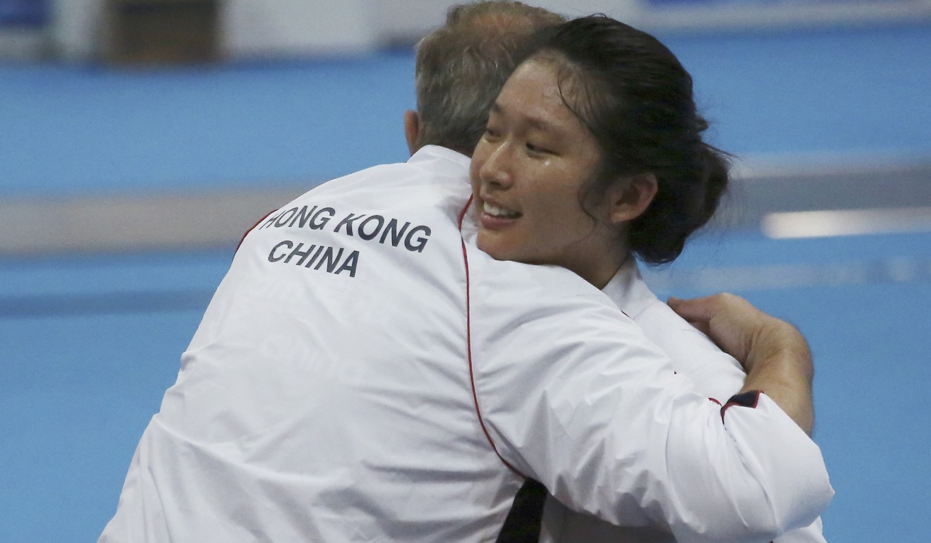 Hong Kong's Vivian Kong gets a hug from her coach after winning her earlier bout.