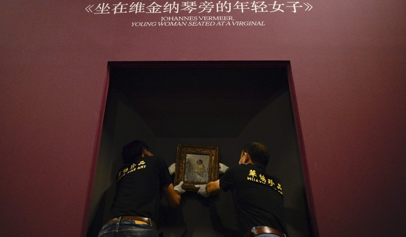 Staff of a professional art transport company hang Johannes Vermeer's ‘Young Woman Seated at a Virginal’ for the Masterpieces from The Leiden Collection exhibition at the National Museum in Beijing. Photo: AFP