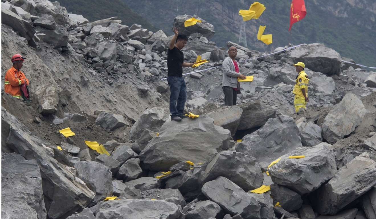 Relatives toss paper offerings to appease the dead at the landslide site at Xinmo village, Sichuan province. Photo: AP