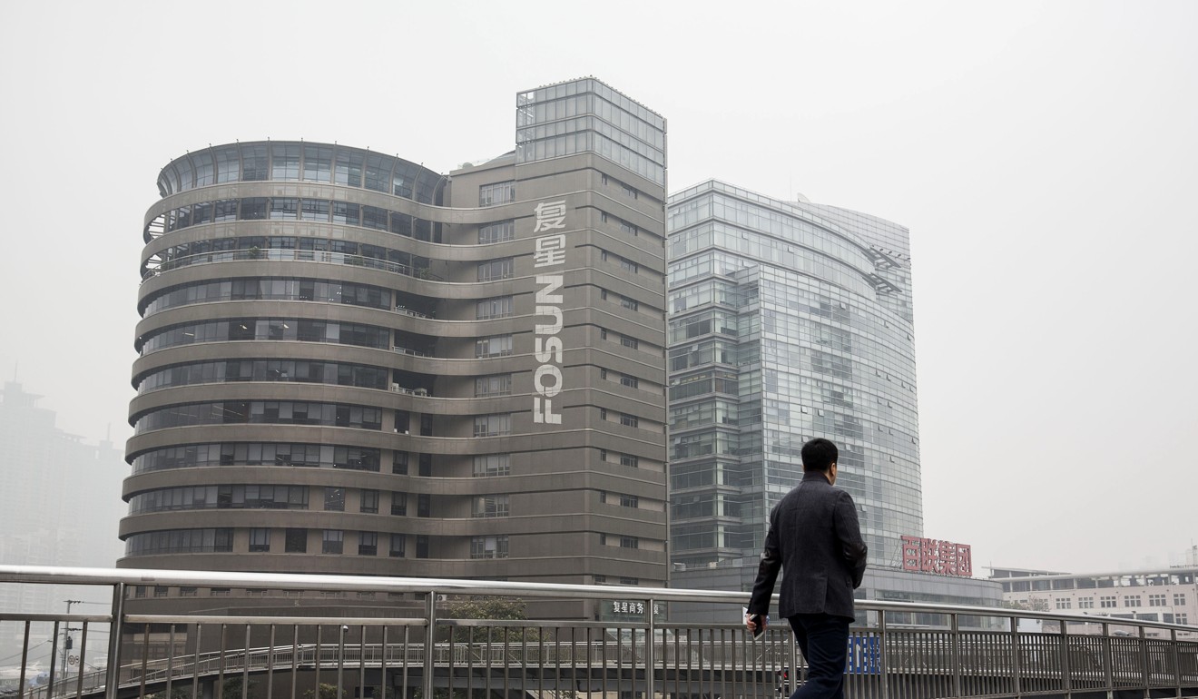 A pedestrian walks across a footbridge in front of the Fosun International Ltd. headquarters building in Shanghai, China, on Friday, Dec. 11, 2015. Fosun bonds plunged by a record and the company suspended its shares in Hong Kong after Caixin magazine reported that billionaire Chairman Guo Guangchang had gone missing. Photo: Bloomberg