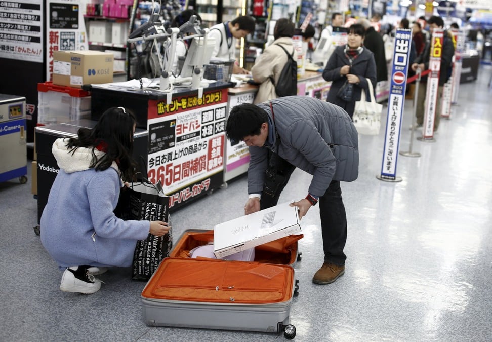 Chinese shoppers packing their shopping into a suitcase at a Tokyo department store. Photo: Reuters