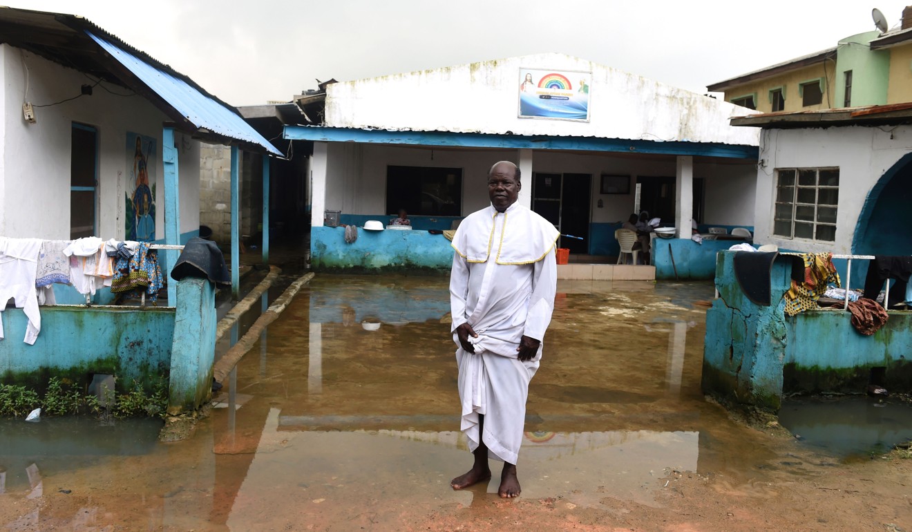 Church leader Taiwo Adesanya stands in front the Crystal Church of God at Owode Onirin in Lagos. Four worshippers were brutally murdered in the church last week. Photo: AFP