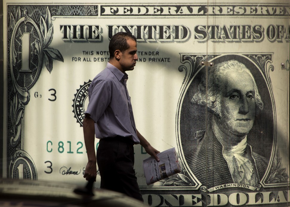 A man walks past a poster showing a U.S. dollar outside an exchange office in Cairo. Photo: AP