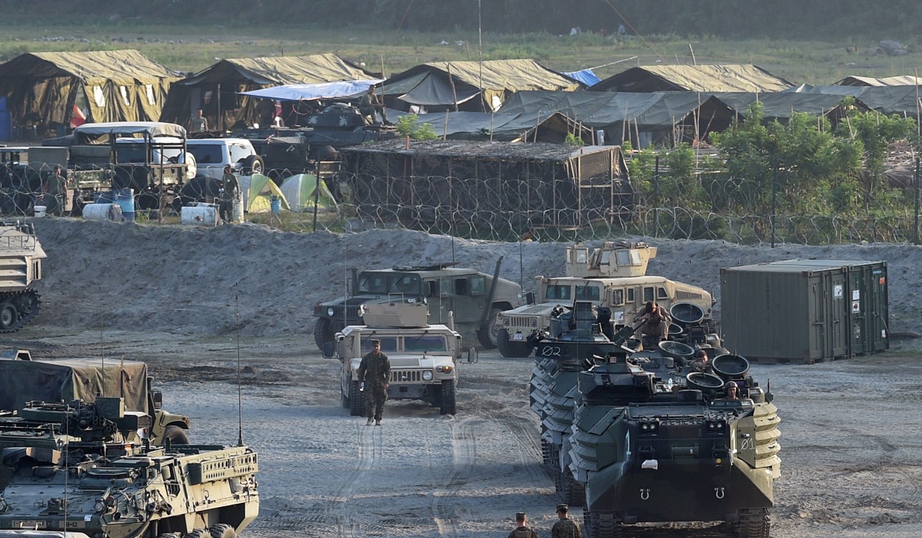 US marines walk next to their transport and amphibious vehicles at a temporary camp for the 