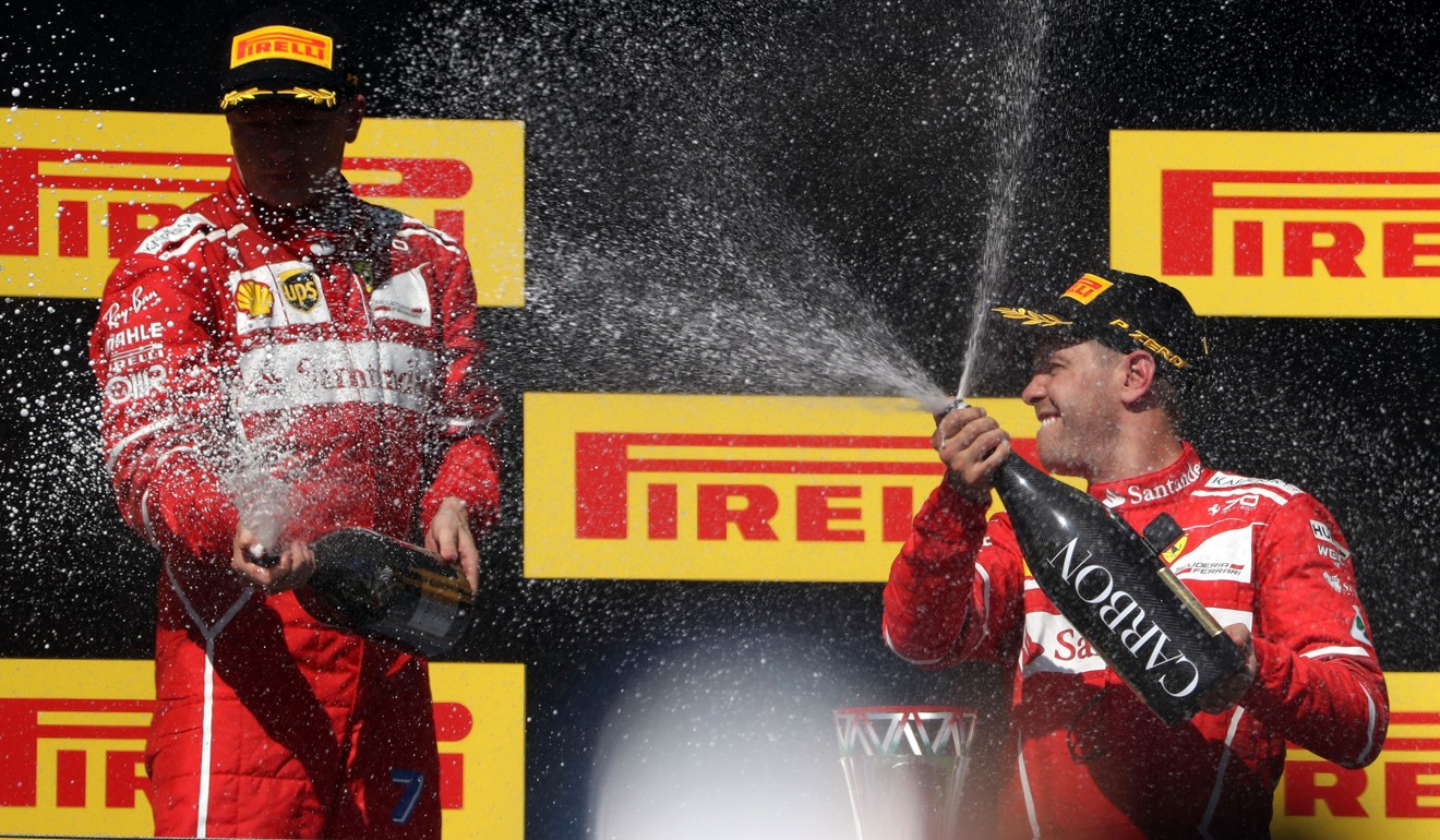 German driver Sebastian Vettel, of Ferrari, (right) celebrates on the podium with second-placed Ferrari's Finnish driver Kimi Raikkonen. Photo: AFP