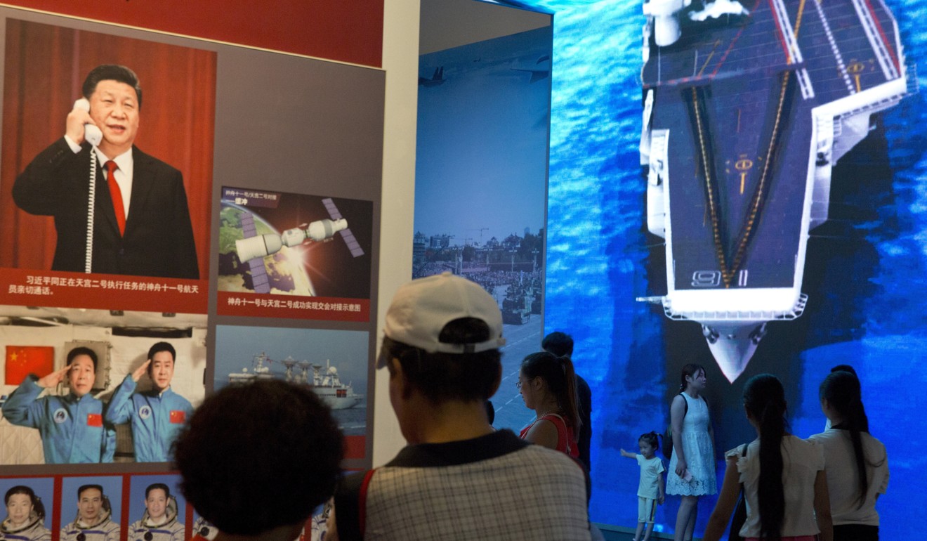 Visitors stand near a photo of Chinese President Xi Jinping and a depiction of the Chinese aircraft carrier during an exhibition to mark the 90th anniversary of the founding of the People's Liberation Army at the military museum in Beijing. Photo: AP