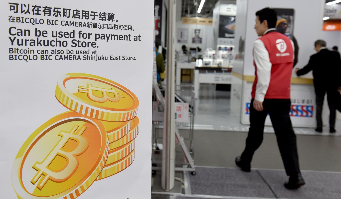 A man walks past a signboard informing customers that bitcoin can be used for payment at a store in Tokyo. Photo: AFP