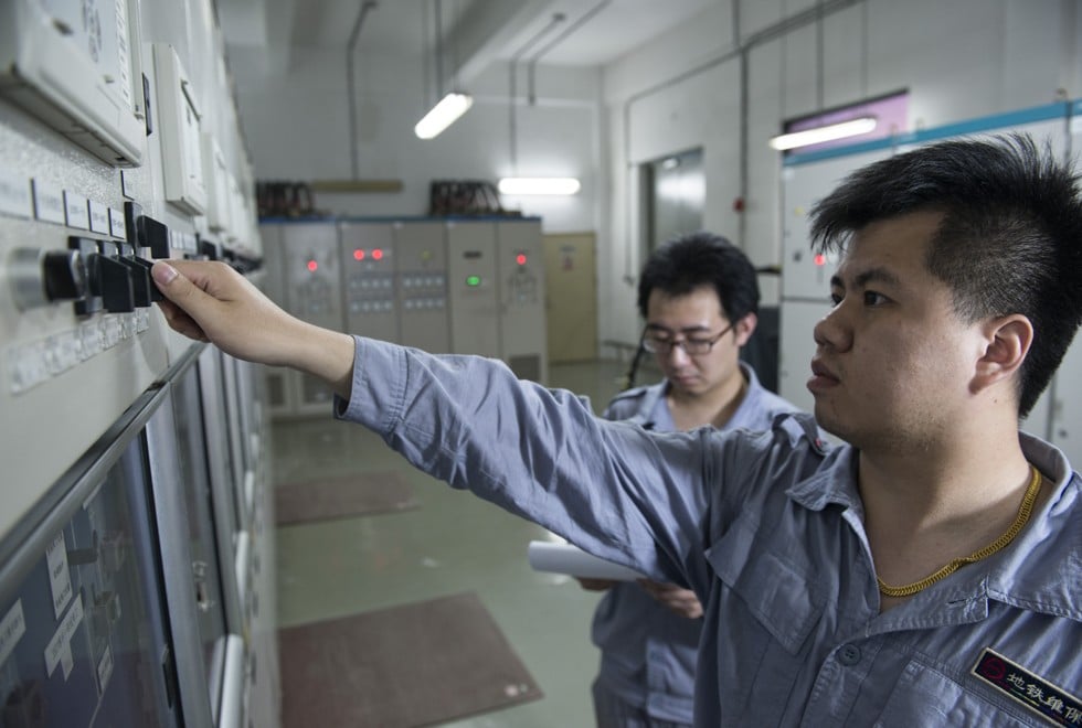Qian Xiaofeng flips a substation switch while colleague Wang Bin looks on.