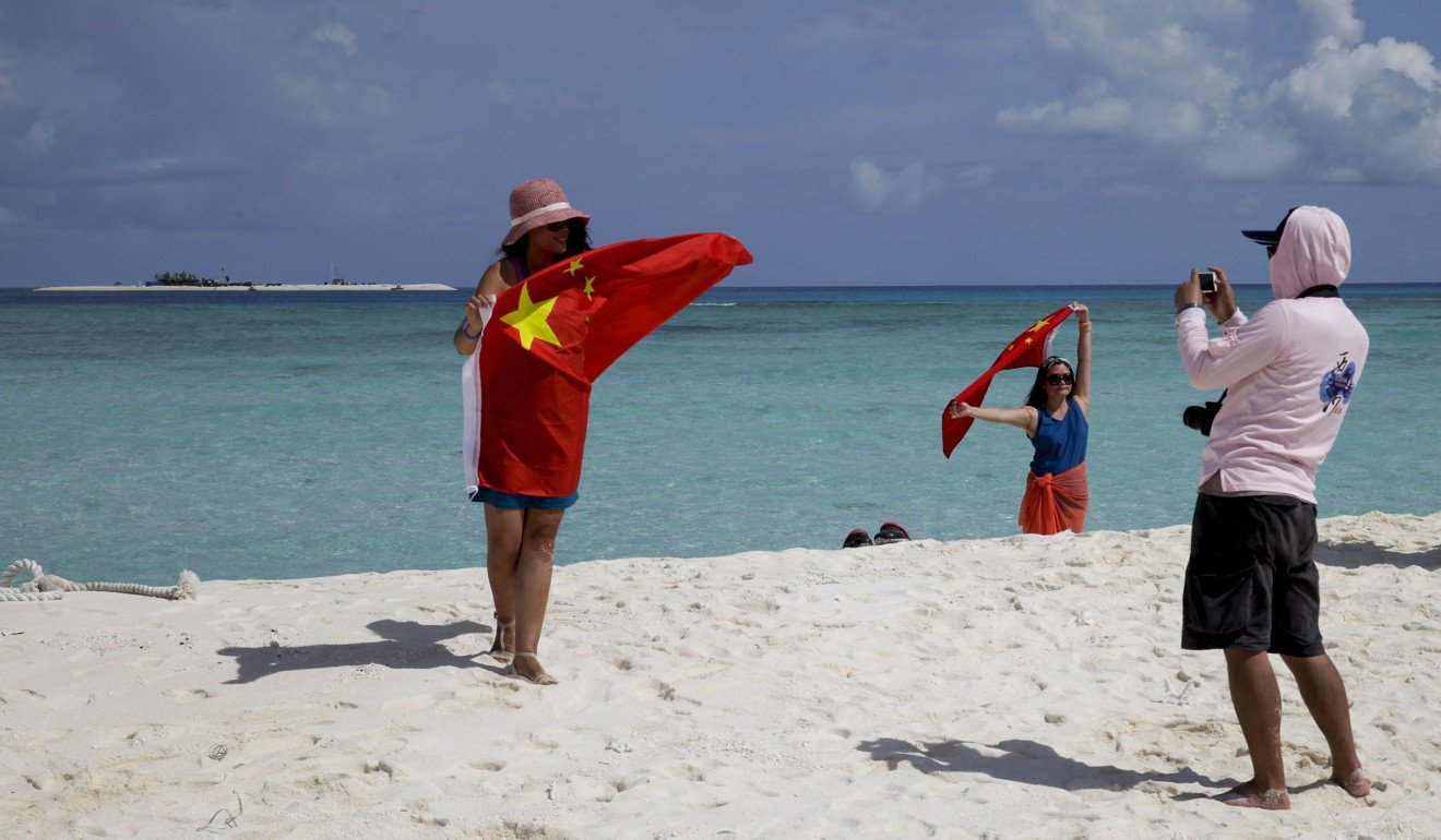 Chinese tourists take souvenir photos with a Chinese national flag as they visit Quanfu Island, one of the Paracel Islands, in 2014. The US Navy – and the world – should be aware that China considers the Paracels to be very different politically and legally from the Spratlys. The former have long been under China’s control and some features and military facilities are substantial and strategic. Photo: AP