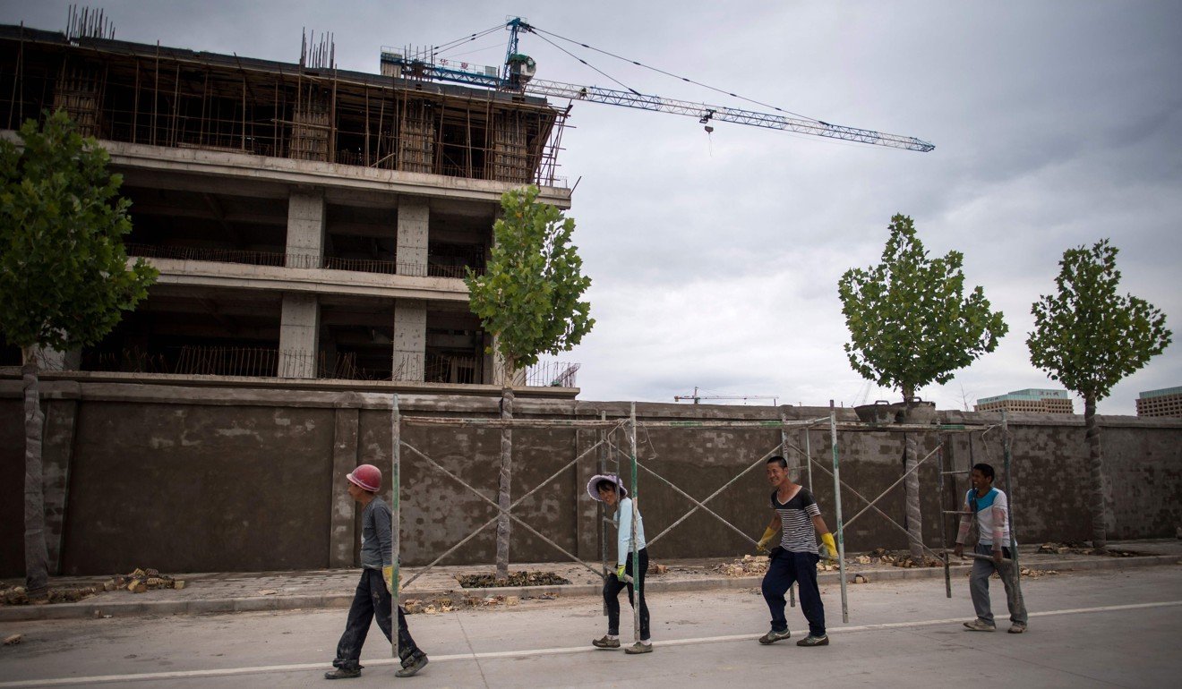 Workers carry scaffolding past a construction site at Kashgar’s Shenzhen City, a development financed by the southern Chinese city. Photo: AFP