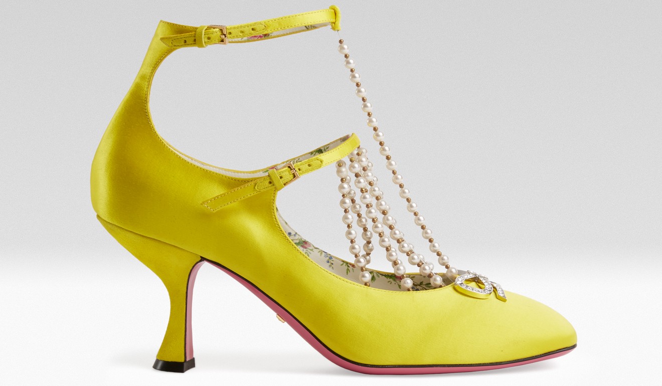 Inspired by Renaissance fashion, the T-strap pump with strings of pearls is made from bold yellow leather, which creates a sharp contrast to the rose print lining and pink painted leather sole.