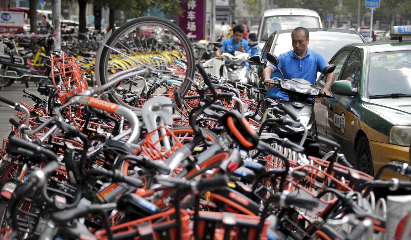 A man on his electric motorbike scooter tries to pass a busy traffic car lane as a stack of shared bicycles block the cycle lane on a street in Beijing.(AP Photo/Andy Wong)