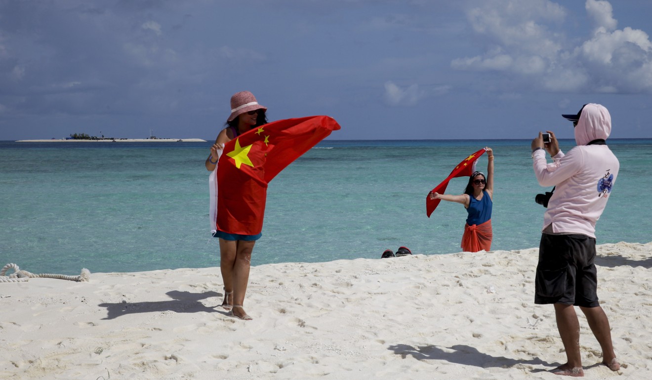 Chinese tourists take photographs with a Chinese flag on one of the disputed Paracel Islands in the South China Sea. Photo: AP