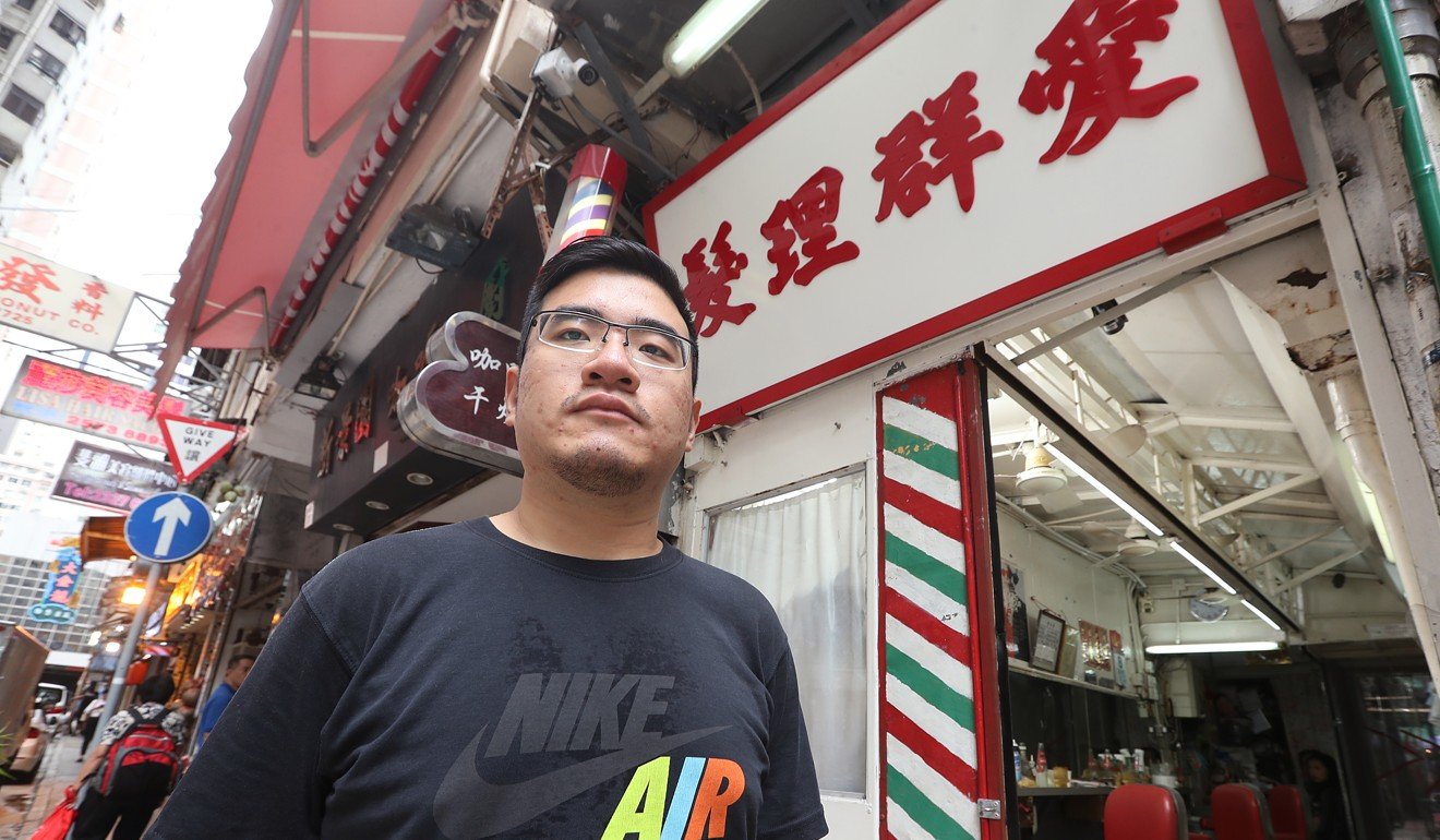Mark Lau, the owner of Oi Kwan Barber's poses for a picture outside his original store in Wan Chai. The government has declared it illegal but given no date when it must close. Photo: Edmond So