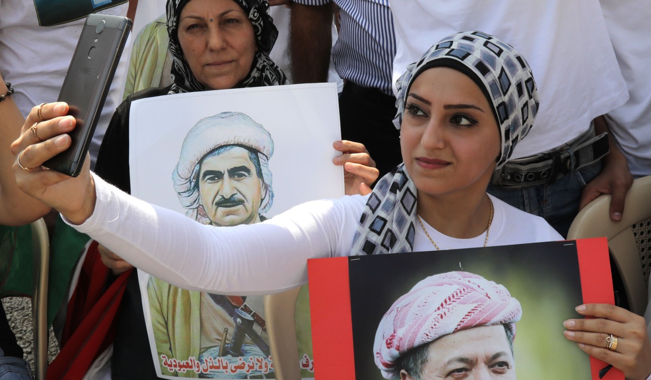 A Lebanese Kurd takes a selfie while holding a portrait of Kurdish regional president Massoud Barzani. Photo: AFP