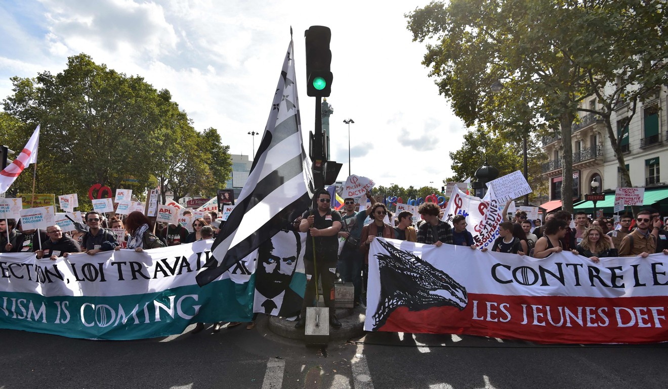 People hold signs and flags during a protest against Macron’s labour reforms in Paris. Photo: AFP