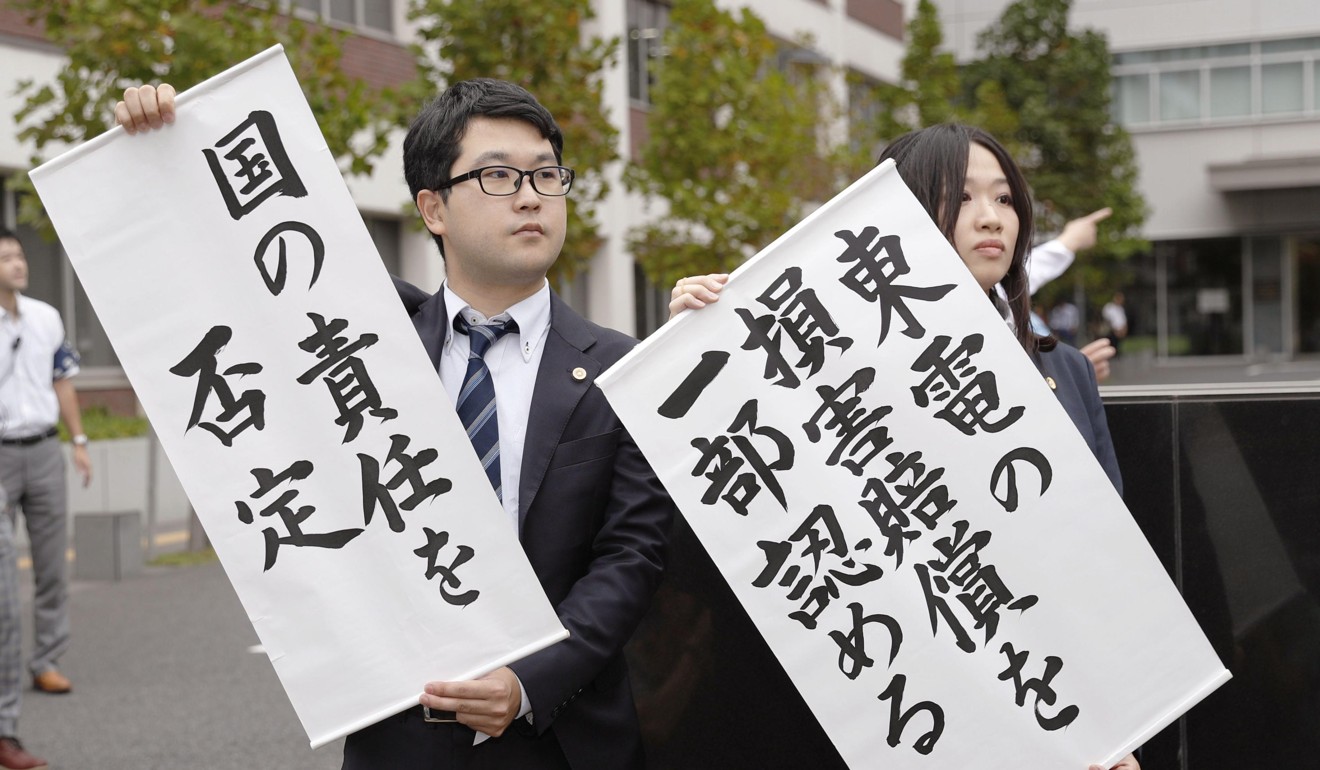 Lawyers representing people forced to evacuate following the Fukushima nuclear disaster hold banners showing a court order demanding that Tokyo Electric Power Company pay damages to the plaintiffs. Photo: Kyodo