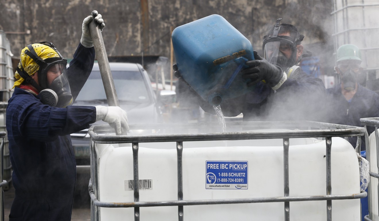 PDEA workers adds neutralising agents to seized chemicals used for the manufacture of illegal drugs in Valenzuela City, north of Manila. Photo: EPA