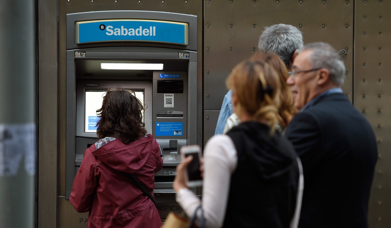 People in Barcelona withdraw money from an ATM during a protest against the Spanish government. Photo: AFP