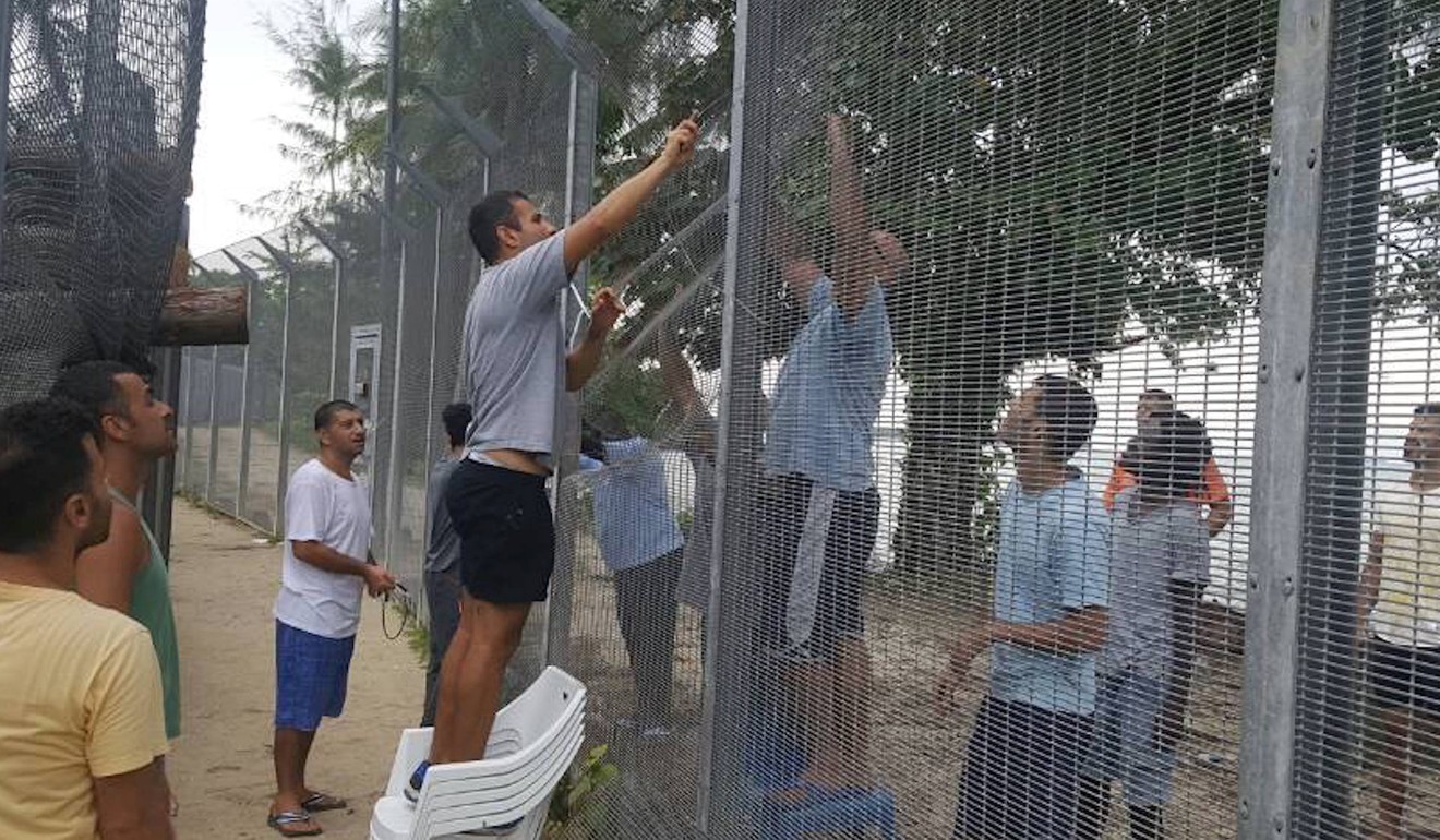 Detainees fix a perimeter fence at the Manus Island detention centre. Photo: Reuters