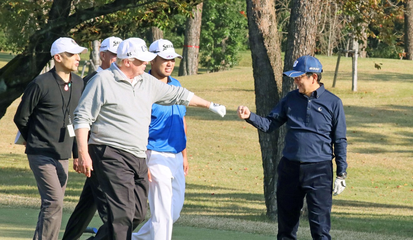 US President Donald Trump fist bumps Japan's Prime Minister Shinzo Abe during a round of golf Sunday. Photo: Kyodo
