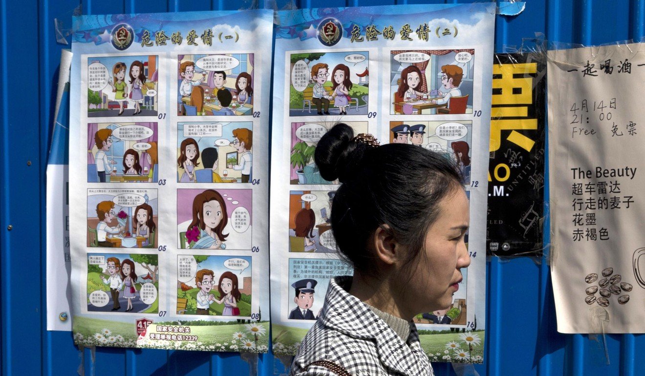 A woman walks past a poster warning against foreign spies displayed in an alleyway in Beijing in April last year. Photo: AP