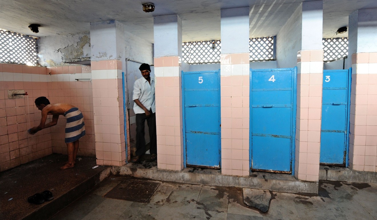 An Indian man washes as another comes out of a cubicle in a toilet complex at a railway station in New Delhi. Photo: AFP