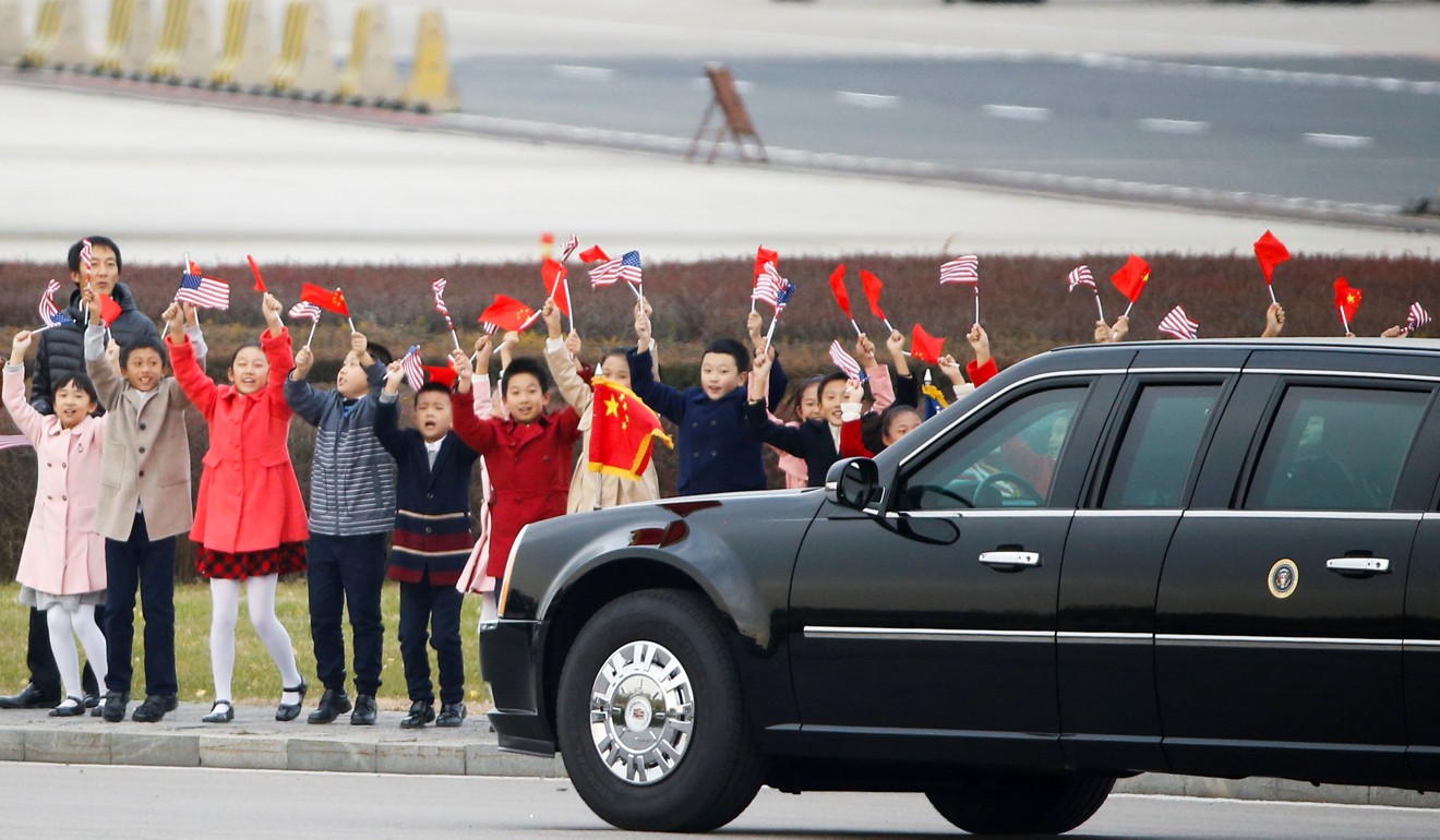 Children wave as the car carrying US President Donald Trump and his wife Melania drives away from Beijing’s airport on Wednesday. Photo: Reuters