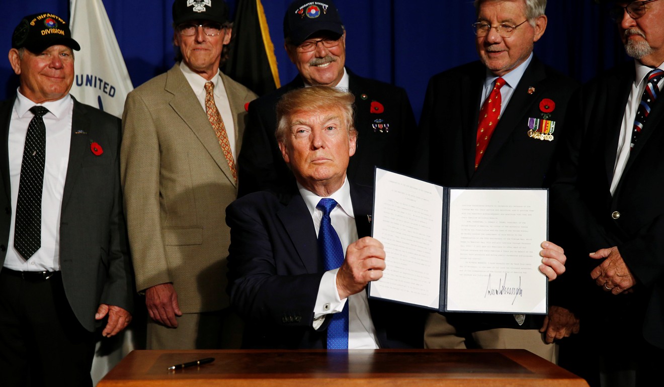 Donald Trump holds up his signed proclamation commemorating the 50th anniversary of the Vietnam War during an event with US military veterans in Danang, Vietnam on November 10, 2017. Photo: Reuters